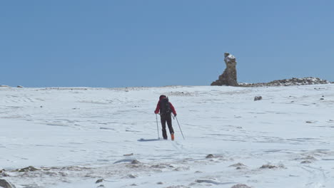 Man-in-skis,-blue-sky-background,-going-up-snowy-Grande-Randonnée,-France,-zoom-out