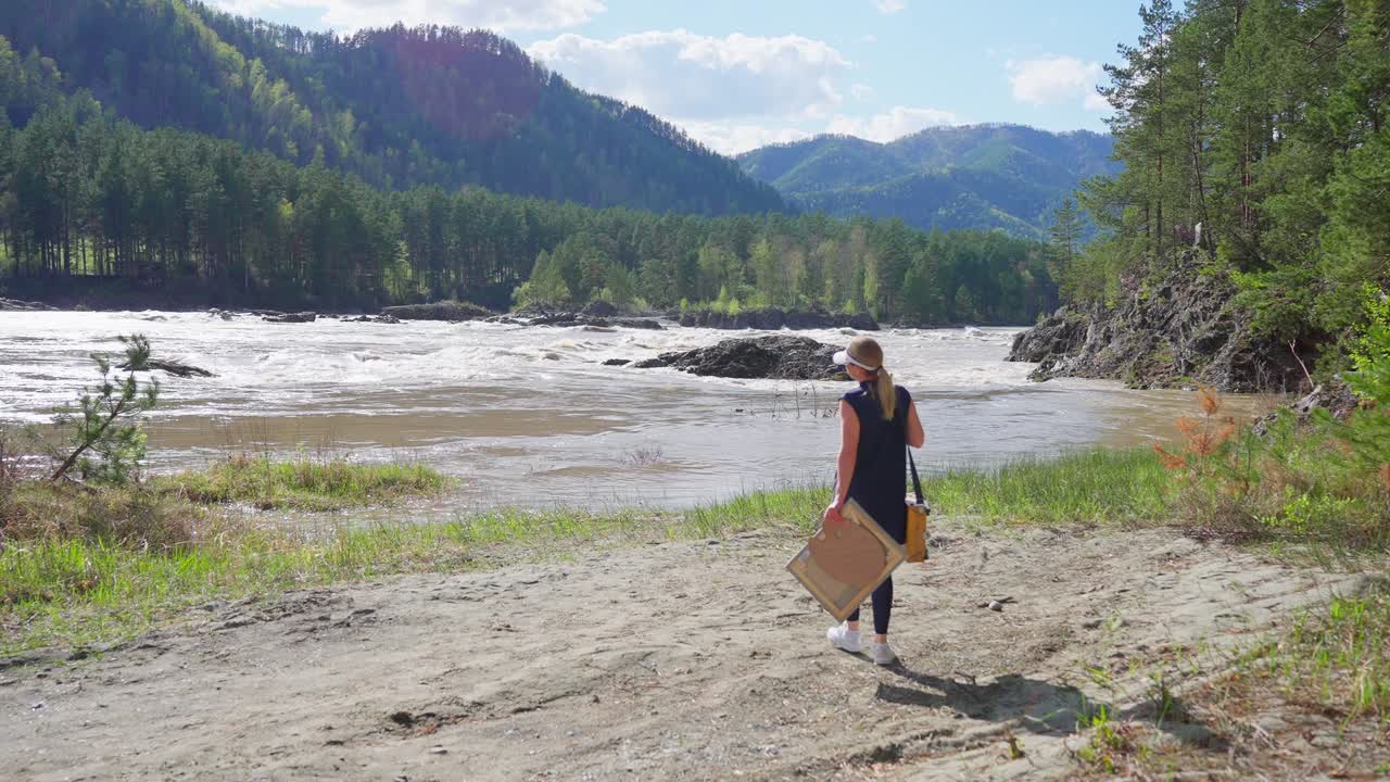 Una donna cammina lungo la riva del fiume trasportando una cassa di legno. Si muove con passo fermo verso l'acqua. Montagne e alberi verdi incorniciano lo sfondo. La scena trasmette un senso di pace e avventura. Ideale per viaggi e natura.