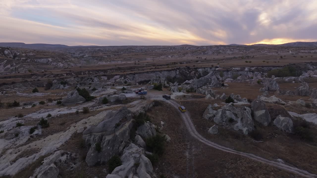 Percorso in fuoristrada nella valle tra formazioni rocciose al tramonto.