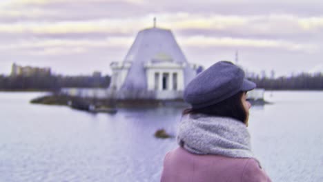 woman looking at a building by a lake