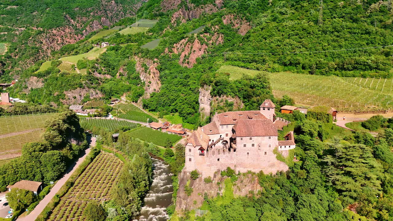 Medieval fortification of Runkelstein Castle on the spur of the rock. River flows at the foot and vast vineyards grow around. Bolzano, South Tyrol, Italy. Aerial view.