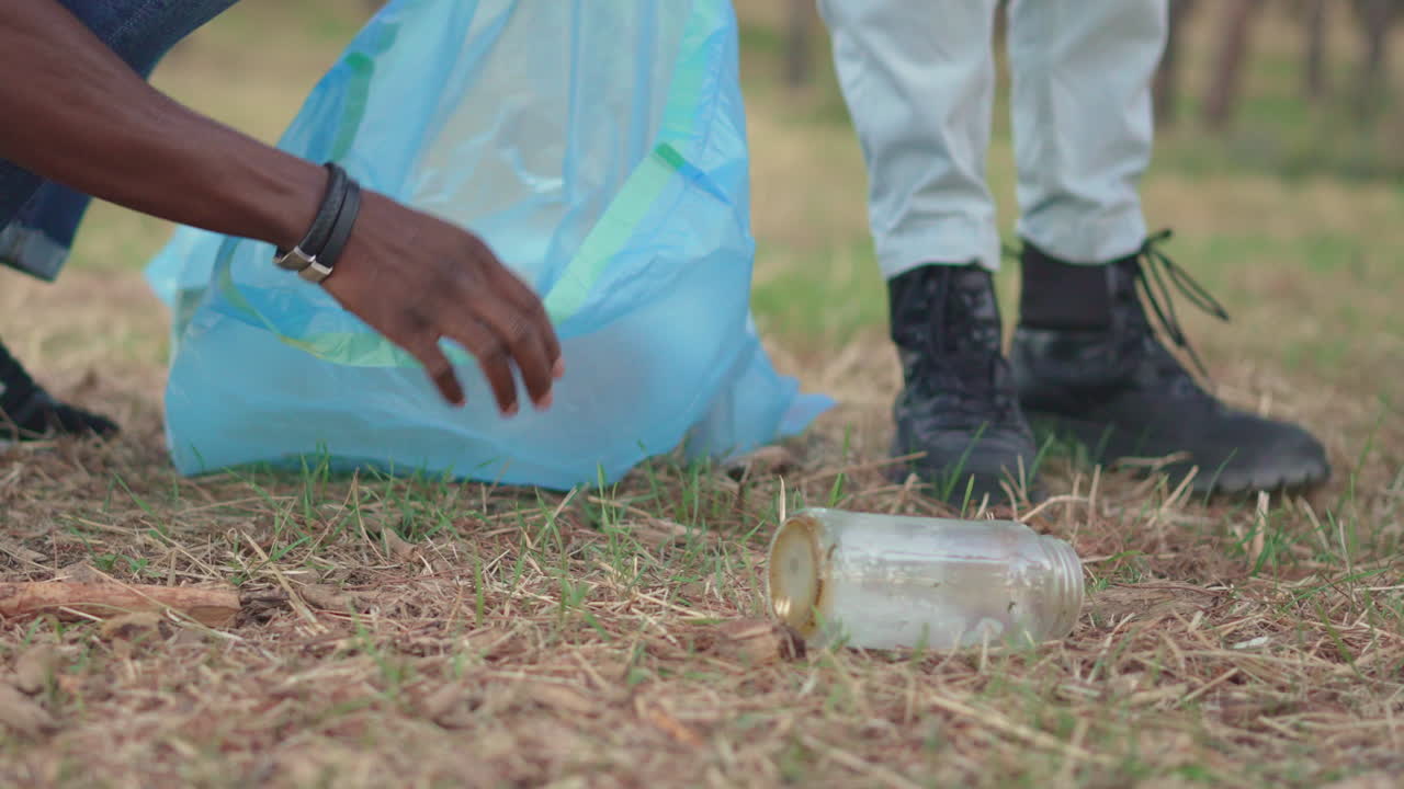 Person cleaning up litter and collecting trash in an outdoor area