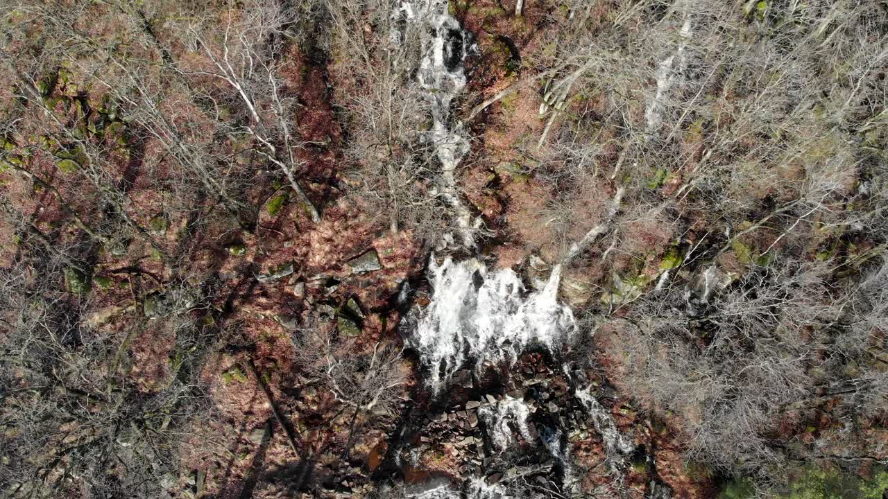 vista aérea de la cascada que brota a través del bosque a fines del invierno