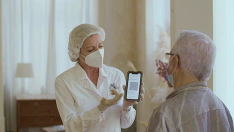 médico alegre mostrando a un hombre mayor su código qr en la pantalla del teléfono