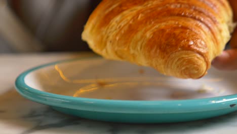 una persona comiendo un croissant en un café