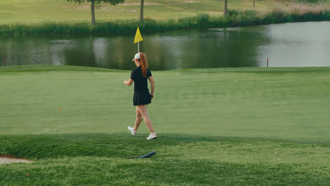 Confident female golfer walks slowly toward the green holding her putter. The slow motion captures poise and focus, highlighting a calm, determined moment during her round on a scenic course.