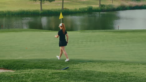confident female golfer walks slowly toward the green holding her putter. the slow motion captures poise and focus, highlighting a calm, determined moment during her round on a scenic course.