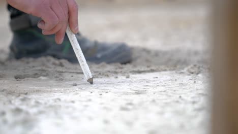 worker's hand drawing line marking on the ground with pencil