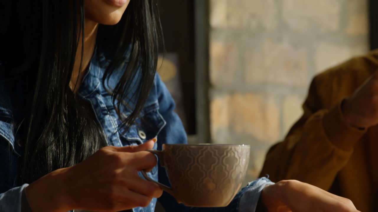 카페 4k에서 커피를 마시고 휴대 전화를 사용하는 젊은 아름다운 혼합 인종 여성의 클로즈업