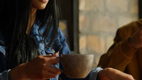 close-up of young beautiful mixed-race woman drinking coffee and using mobile phone in cafe 4k