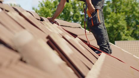 Side-view-of-worker-fixing-the-tiles-on-rooftop-of-hut-for-installation-of-solar-panels