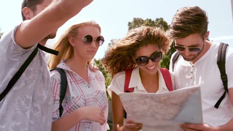 Smiling-hipster-friends-pointing-direction-while-holding-map