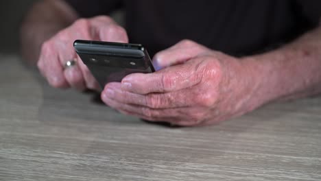 las manos de los ancianos usan un teléfono inteligente para navegar por la web y enviar correos electrónicos