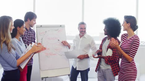 Executives-applauding-their-colleague-while-giving-presentation-on-flipchart-4k