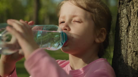 thirsty little child drinks clear fresh water at tree trunk