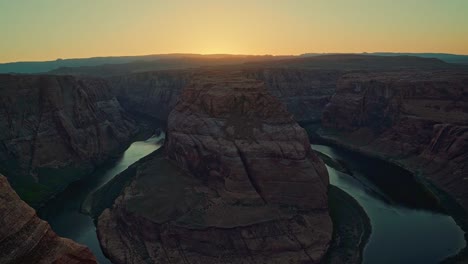 extreme wide tilt up landscape shot revealing the famous horseshoe bend colorful sandstone rock formation formed from the colorado river near page, arizona during a sunny spring desert sunset at dusk