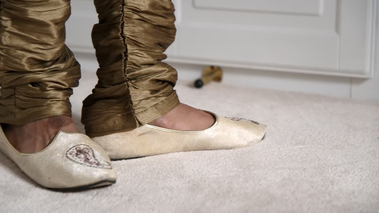 Close-up of an Indian groom’s feet as he steps into traditional male wedding shoes, capturing a key moment in ceremonial preparation