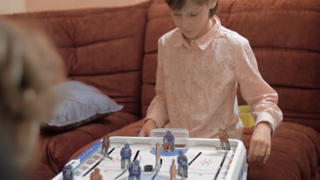 girl and boy playing table hockey at home