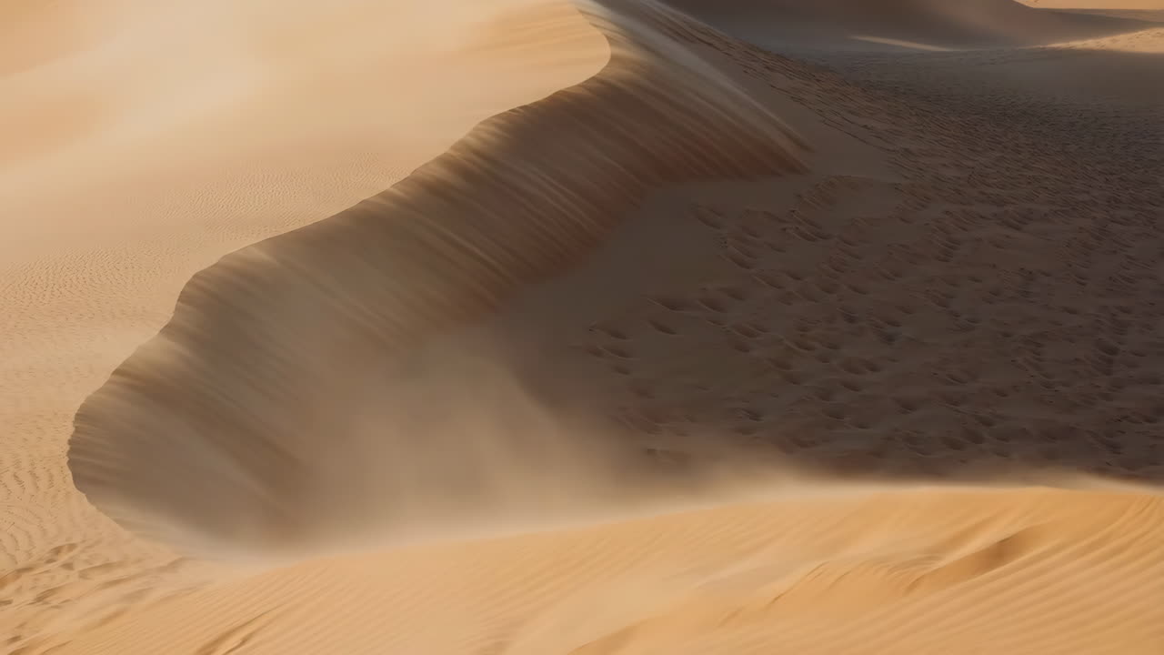 Wind blowing sand across a golden desert dune