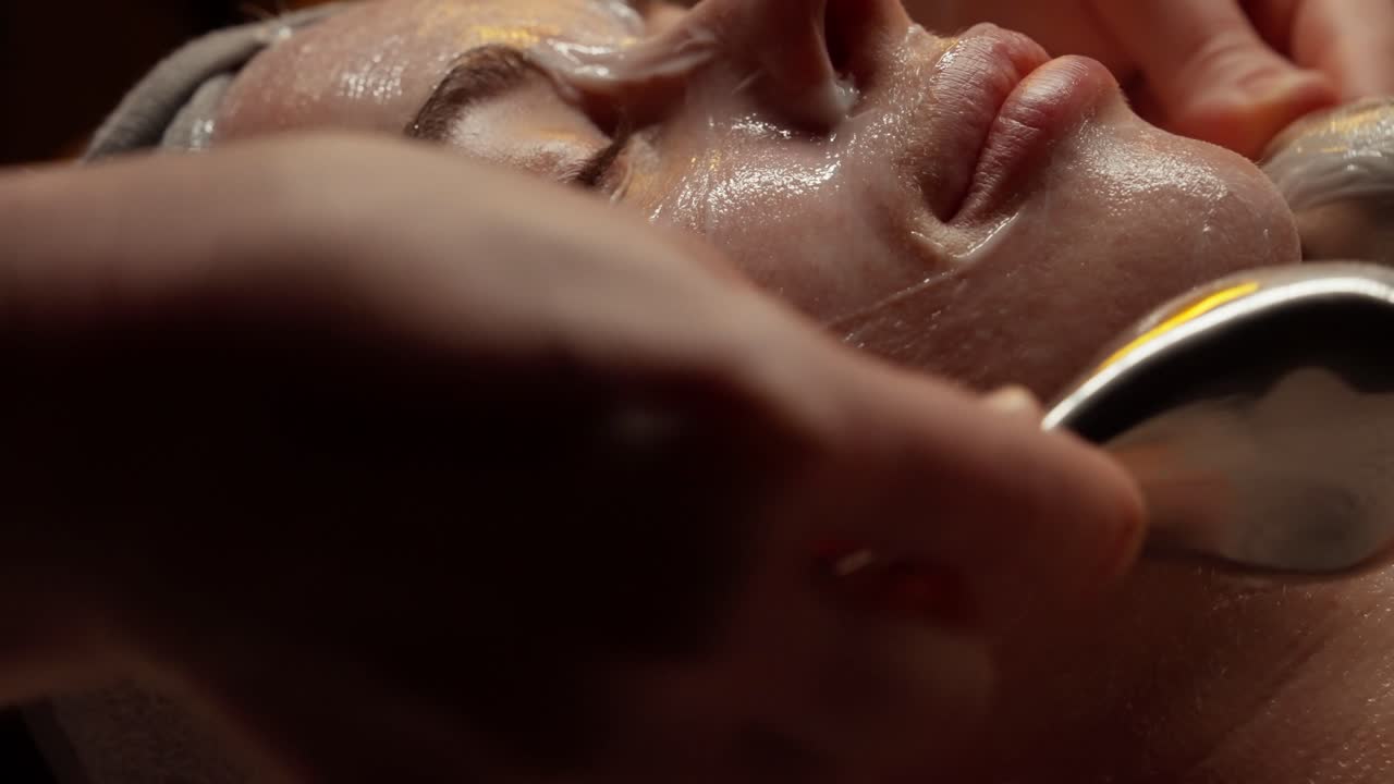 Primo piano di una donna che riceve un massaggio facciale con strumenti metallici