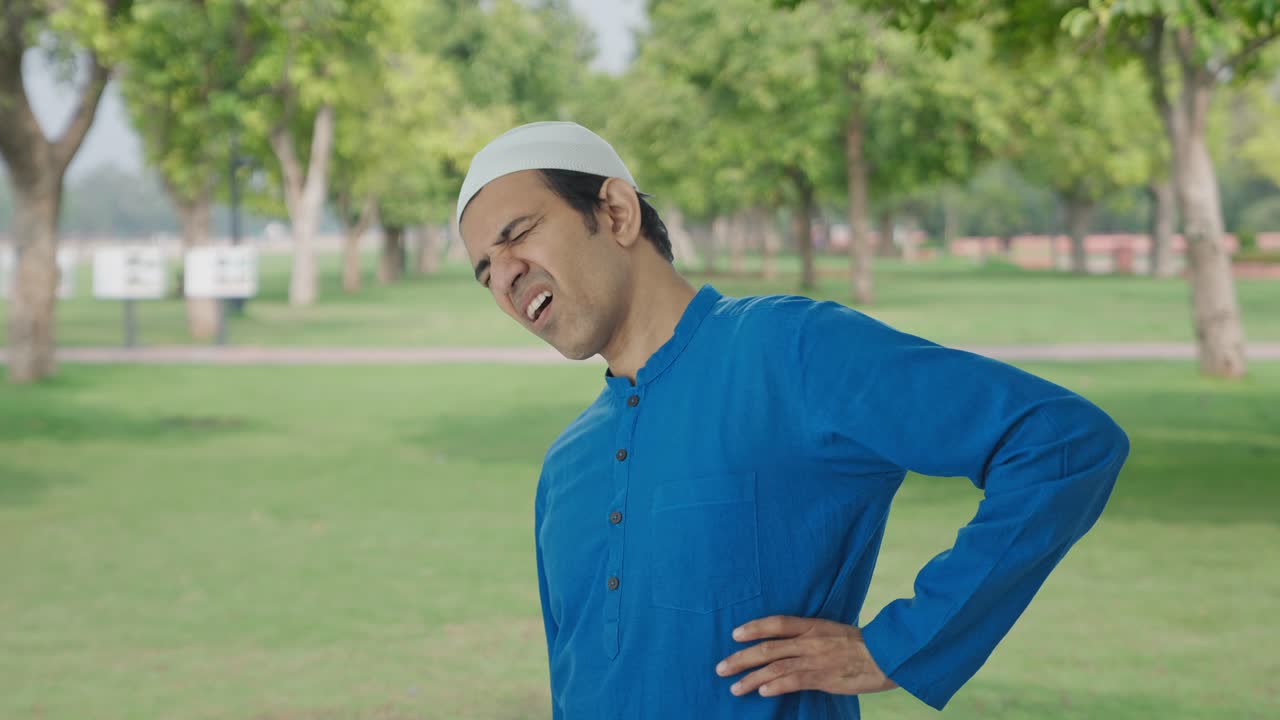 公園で背中の痛みで苦しんでいるイスラム教徒の男性