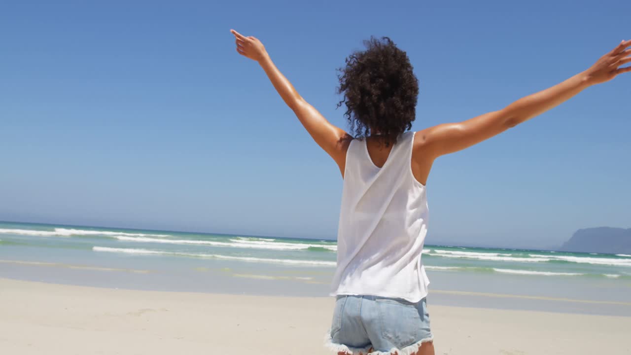 mujer de pie con los brazos extendidos en la playa 4k