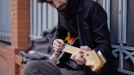 guy playing on the guitar with a pick on the street