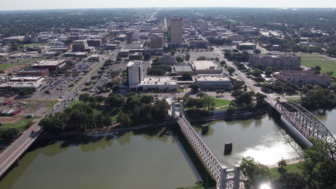 4K parallax drone footage of downtown Waco, Texas featuring the Suspension Bridge and Brazos River, showcasing the skyline, riverfront scenery, and smooth cinematic motion.