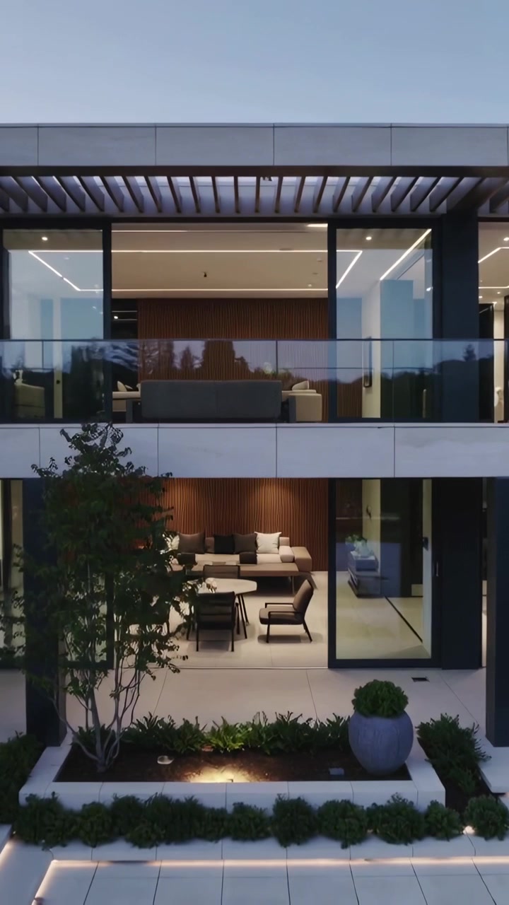 Video vertical: Dron alejándose mostrando una casa de dos pisos al anochecer, revelando el patio y luces LED.