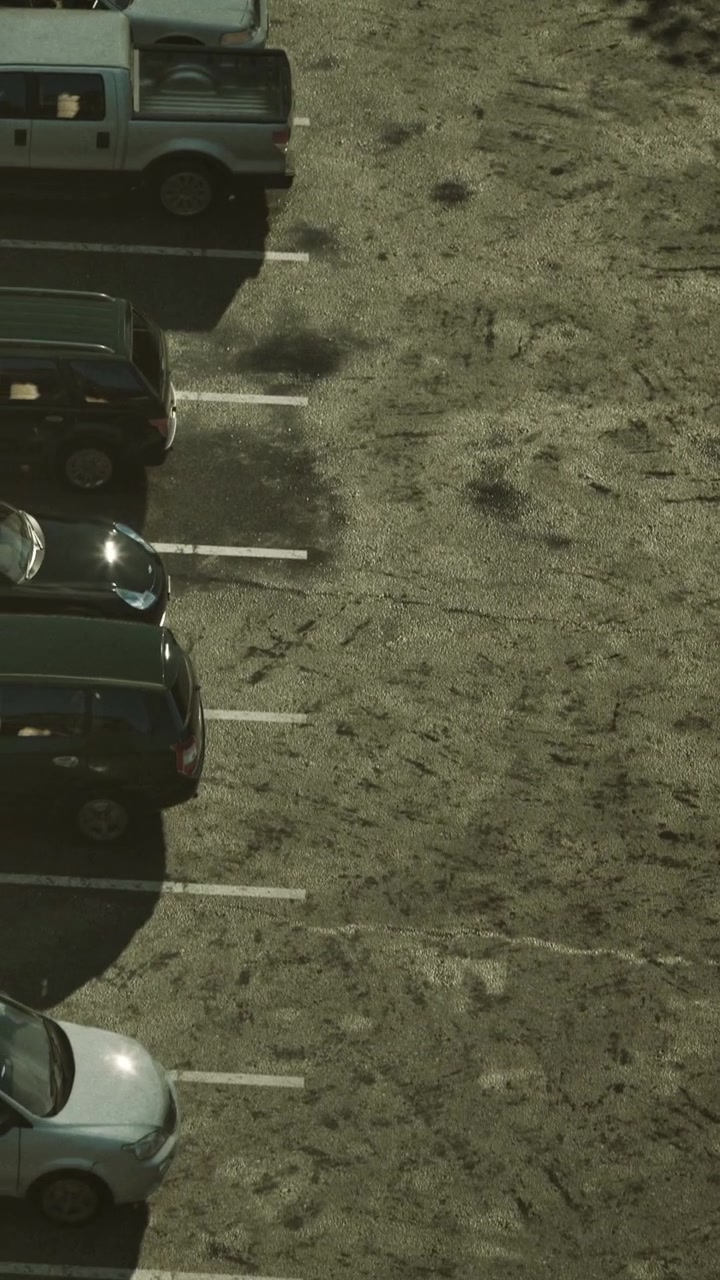 Many vehicles parked in rows in a lot with visible ground patterns