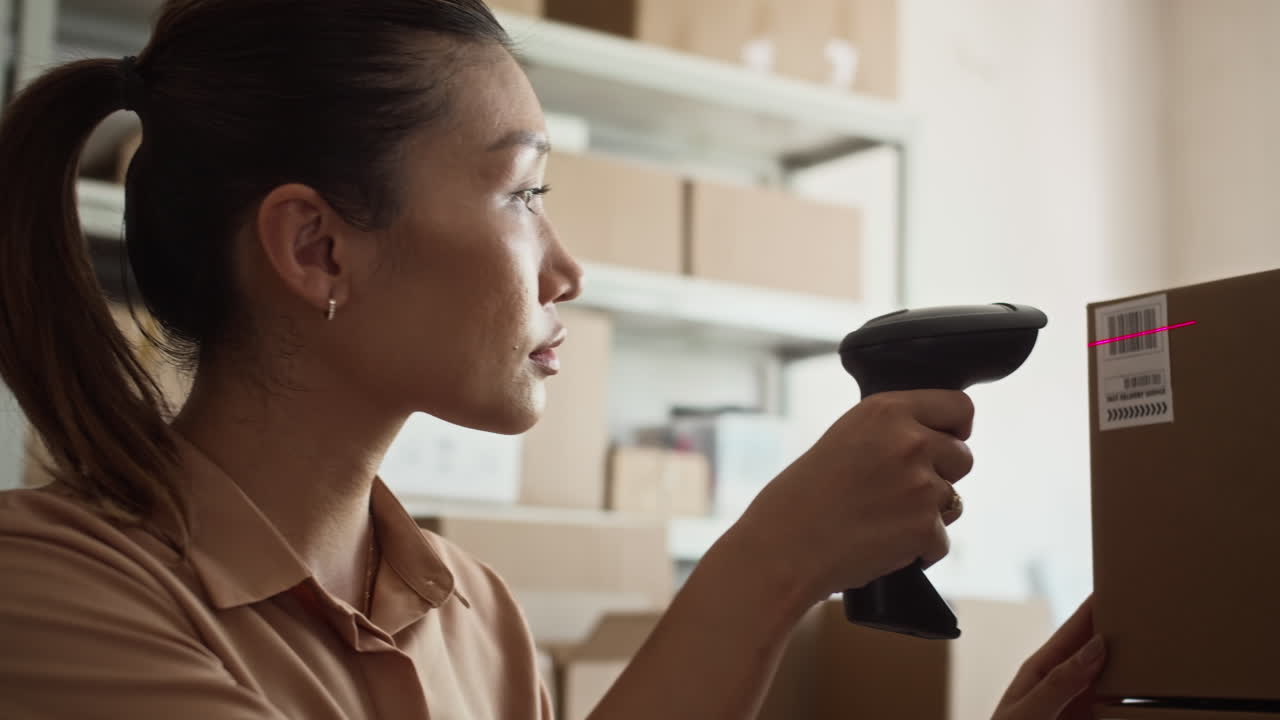 Asian Delivery Service Worker Using Scanner on Parcels in Boxes for Shipping