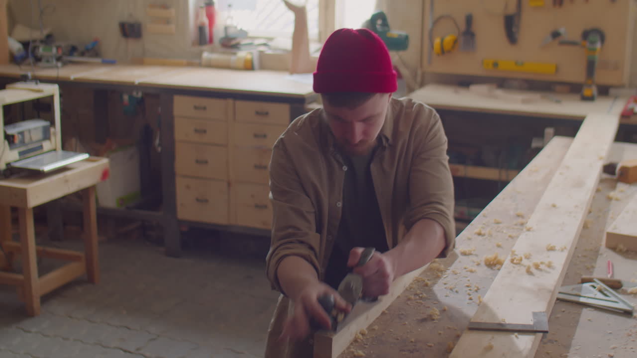Woodworker Using Hand Plane and Double Square in Carpentry Workshop