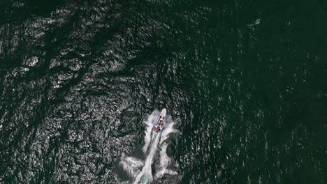 Extreme-jet-boat-roaring-across-the-sea-with-tourists,-Aerial-footage