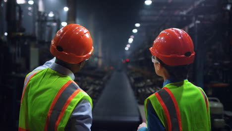 Focused-engineers-discussing-work-at-huge-energy-manufacturing-tyre-factory.