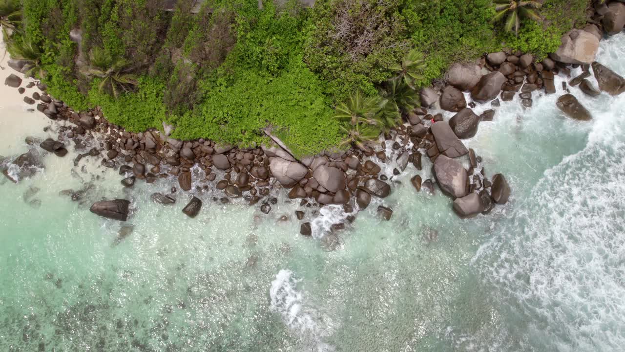 Drone footage of Anse forbans beach, transparent clear water, near granite stones and coconut palm trees, Mahe, Seychelles 30fps 1