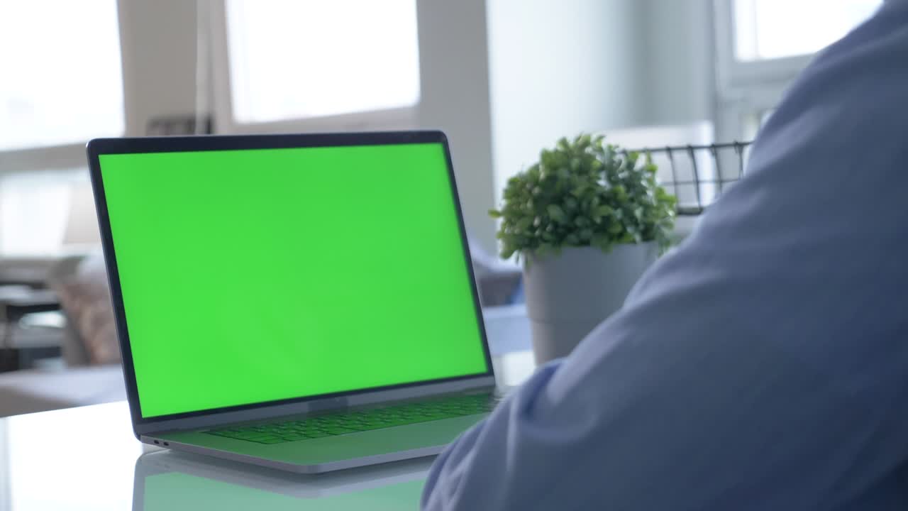 Close-up of male hands using green screen chroma key laptop typing working in light office with modern computer. Technology, copyspace and job concept