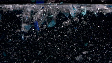 stones falling into glitter water in slow motion with lots of bubbles