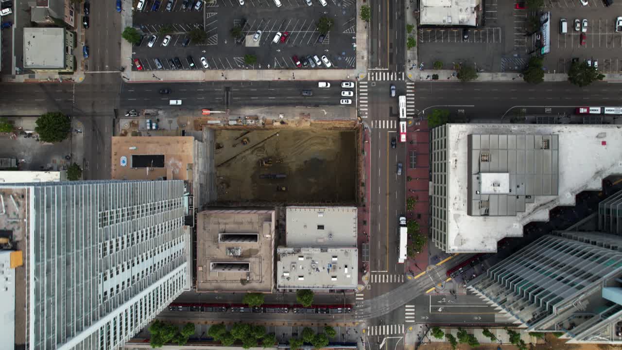 Drone voando para trás com a câmera apontada para baixo, capturando ruas, telhados e edifícios no centro de San Diego.