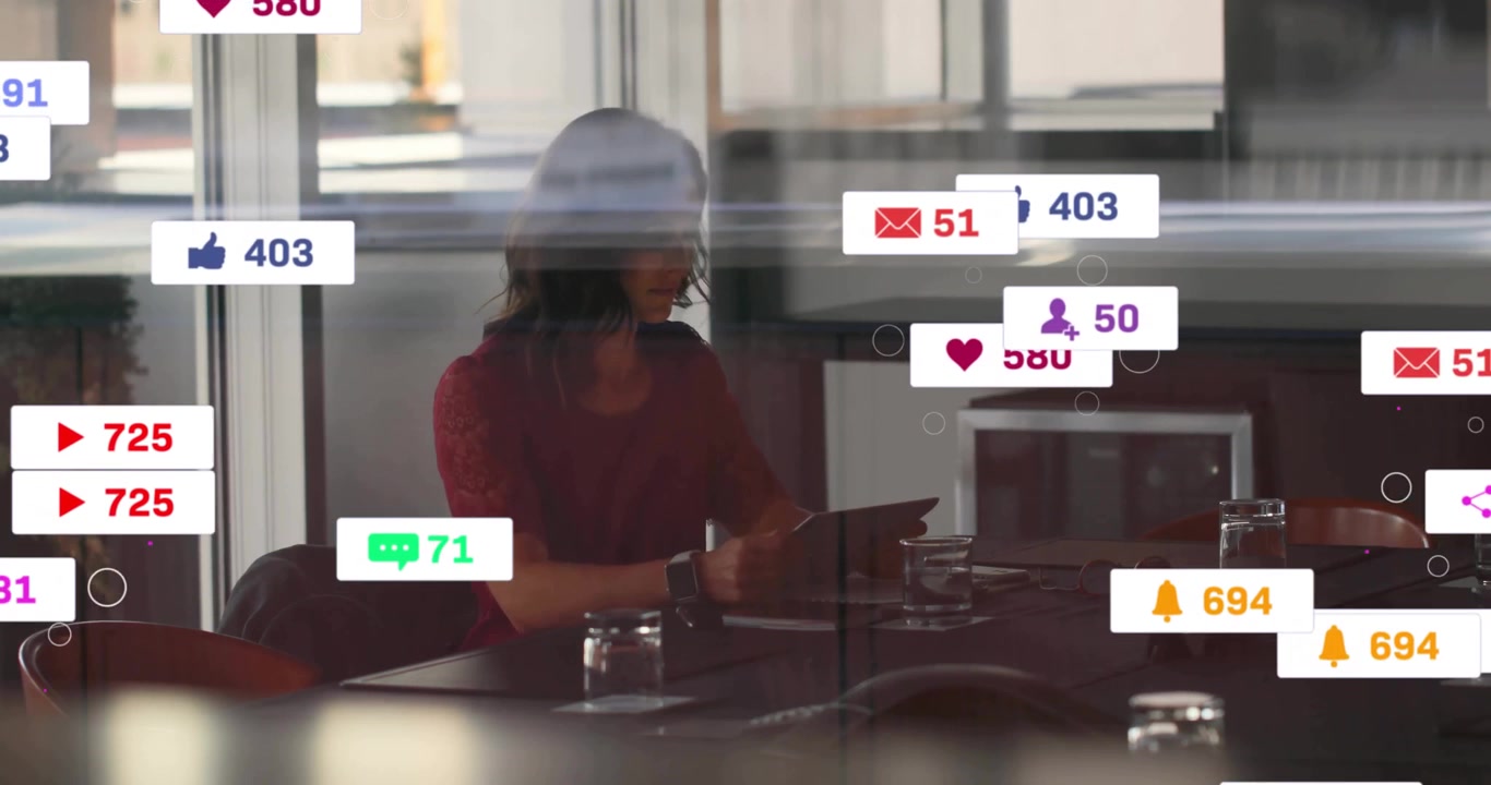 Woman holding tablet, seated in business meeting room, showing floating social media alert icons