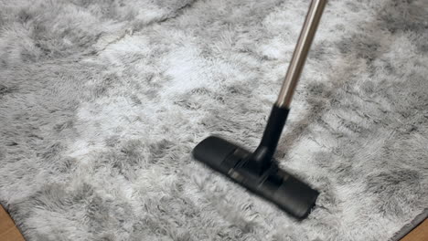 a vacuum cleaner cleaning a silver grey rug vacuuming on a carpet at home