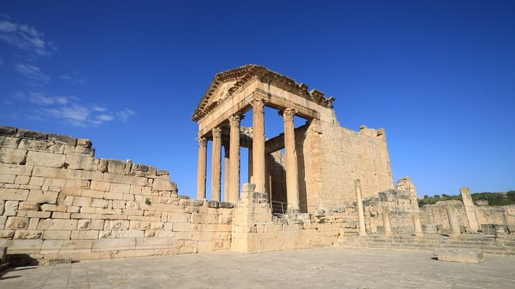 Antiche rovine romane a Dougga sotto un cielo azzurro e limpido, inquadratura ampia