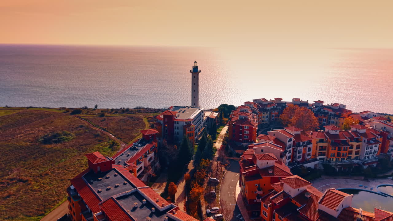 Il faro di Aheloy si erge su un paesaggio marino illuminato da un sole al tramonto. Filmato aereo sulle incantevoli case colorate. Bulgaria