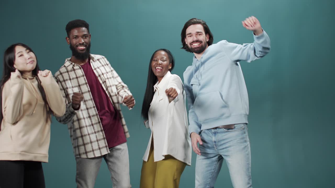 Friends are having fun and dancing together in casual clothes on the green background
