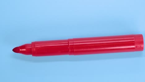 red marker pen rotating on blue surface background, macro shot close up view detail