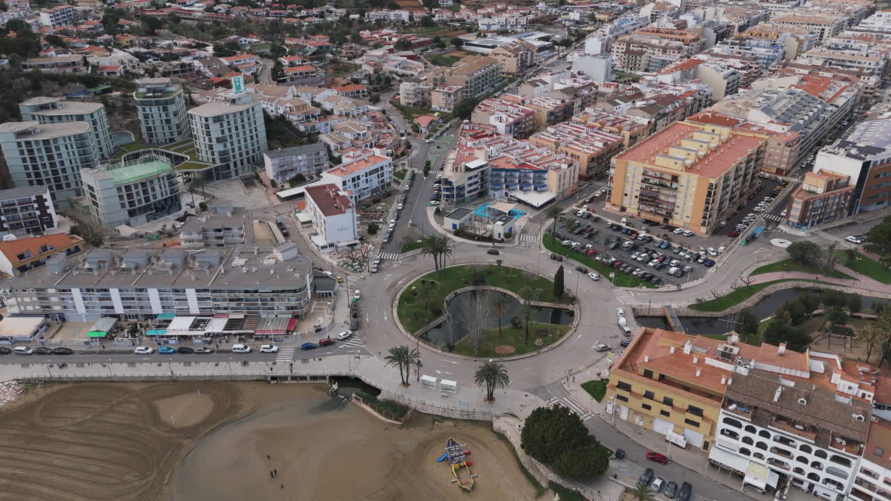 Drone flight over Playa Sur beach shows people walking shoreline with distant cityscape