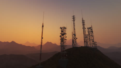 Cámara-Panorámica-Que-Muestra-Un-Complejo-De-Antenas.-El-Mástil-De-Radio-Sostiene-Antenas-Para-Telecomunicaciones,-Radiodifusión-Y-Televisión.-Estructuras-Altas-Con-Montañas-Y-Un-Cielo-Al-Atardecer-De-Fondo.-4k