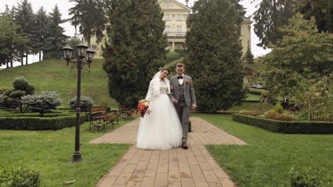 Encantadores-Recién-Casados-Novia-Caucásica-Novio-Caminando-En-El-Parque,-Tomados-De-La-Mano,-Pareja-De-Novios-Familia