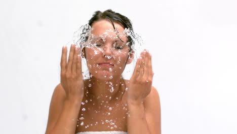 mujer salpicándose la cara con agua