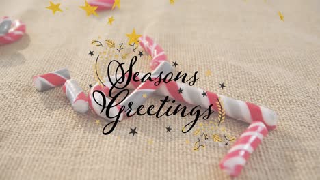 animation of seasons greetings text and stars over candy canes on beige backrgound