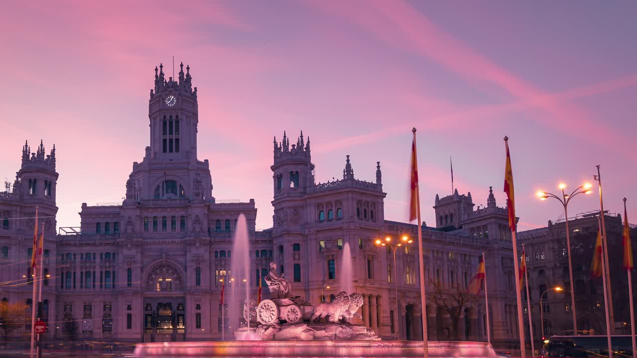 Detailní úvodní záběr. Časosběr východu slunce nad radnicí města Madrid Casa de Correos a náměstím a fontánou Cibeles, přechod z noci do dne